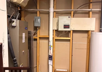Unfinished utility room with exposed wall studs, HVAC system, water heater, and electrical panels.
